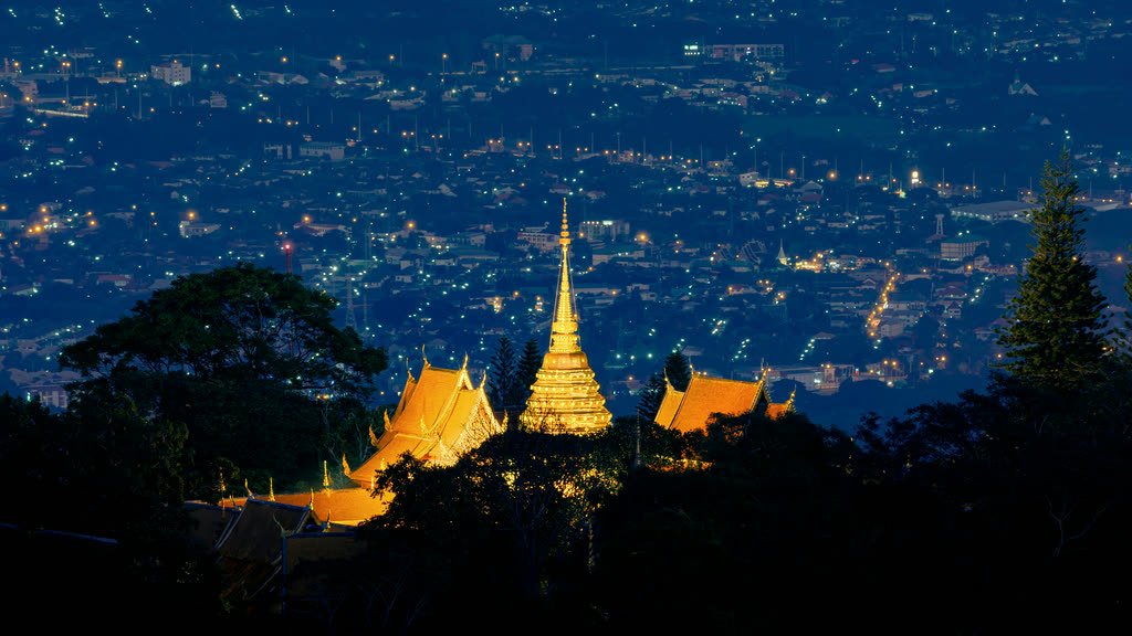 Wat Phra That Doi Suthep lit up at night, with the lights of Chiang Mai city spread out below