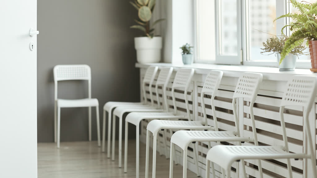 A row of empty white chairs in a waiting room
