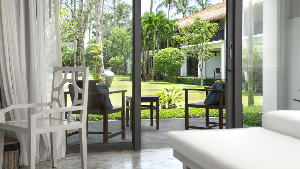 A bright room with an open door to a tropical garden terrace