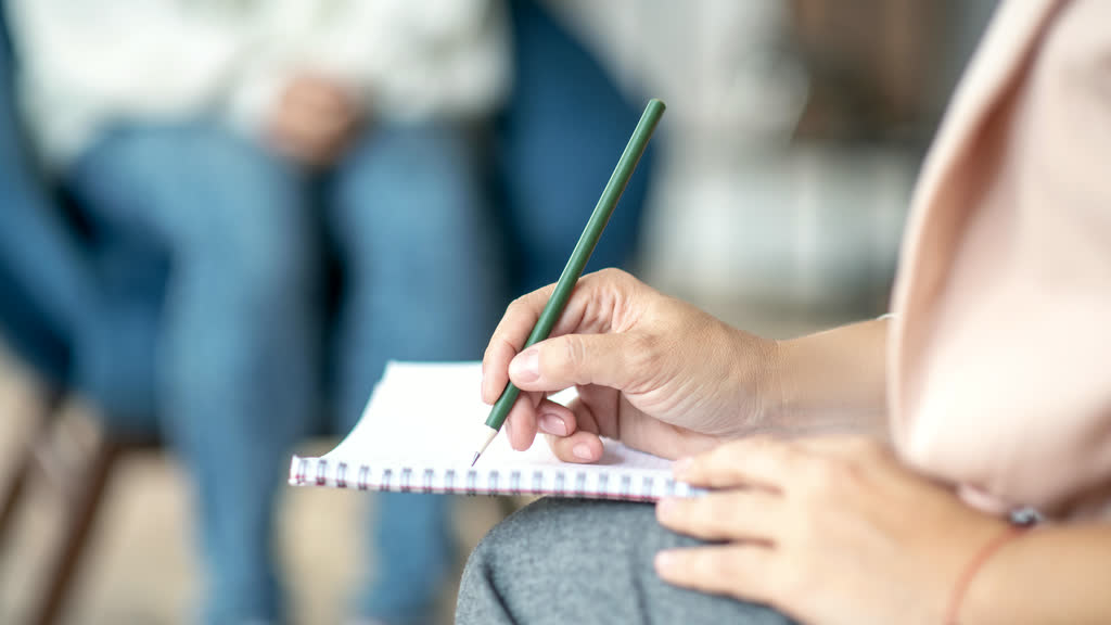 A counsellor writing notes in a notebook during a session