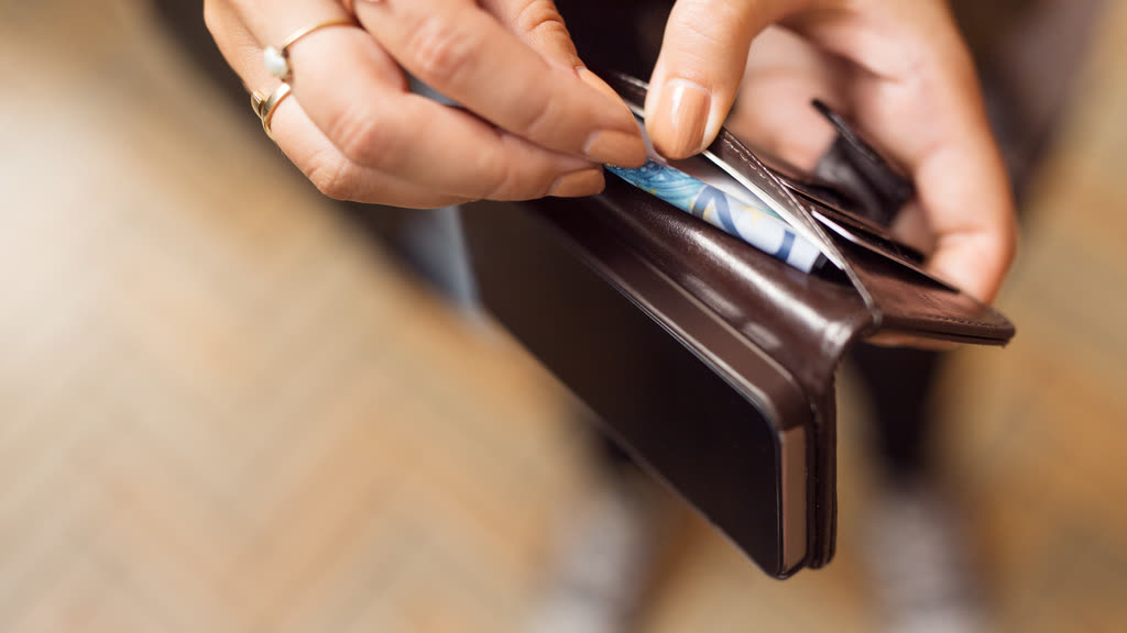 Hands holding an open leather wallet with cards