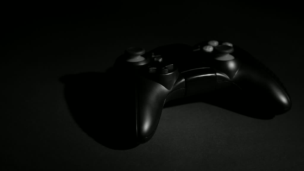 A black game controller resting on a dark surface
