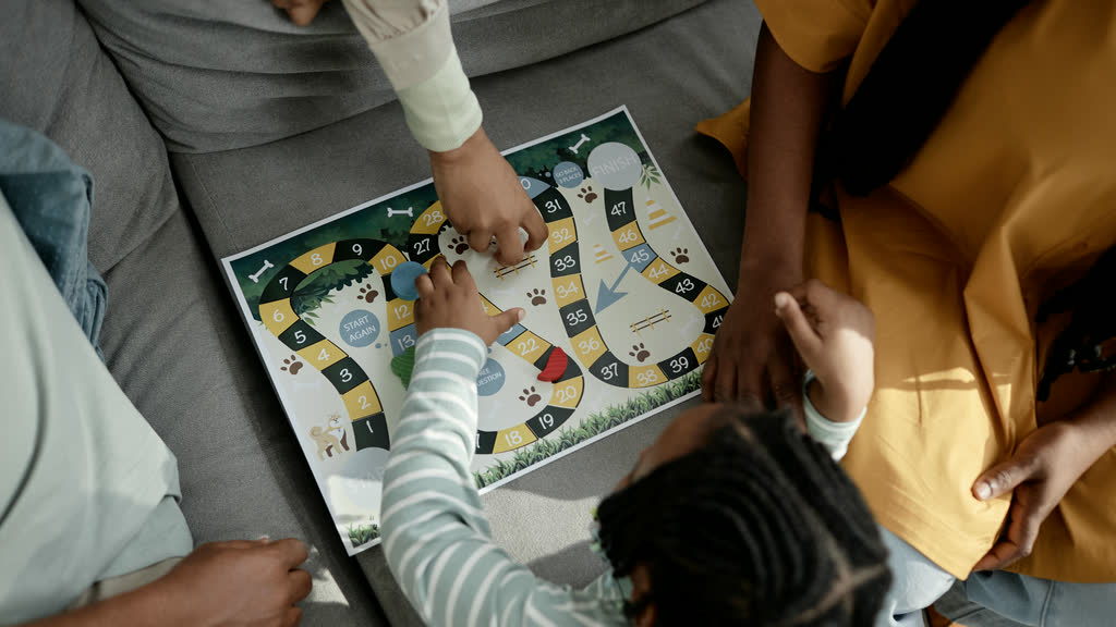 A family playing a board game together on a sofa, seen from above