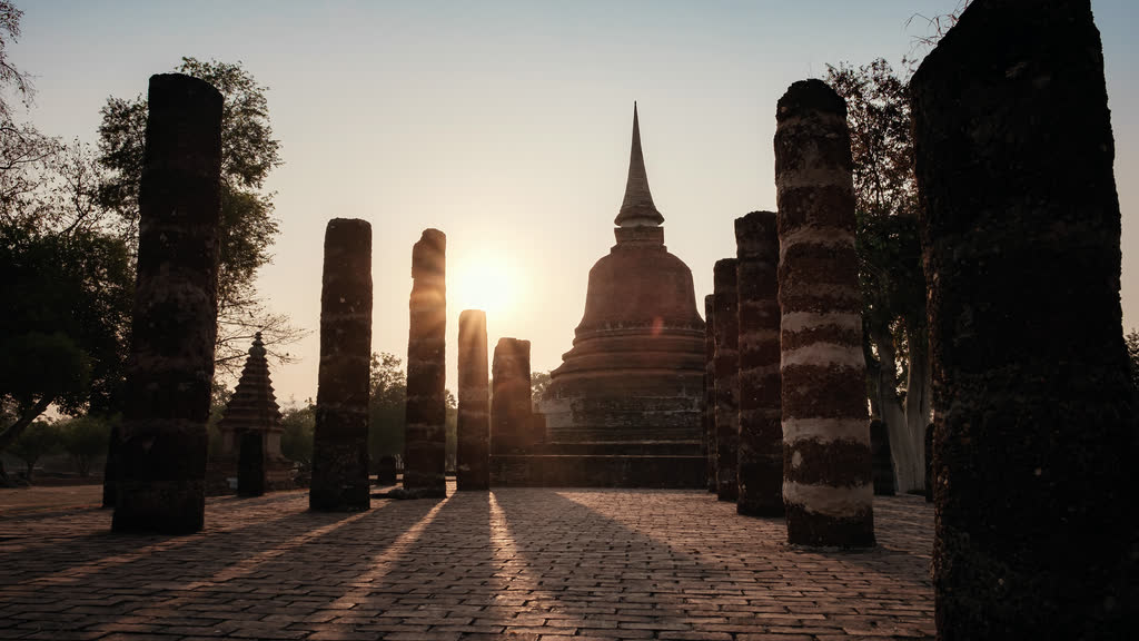 Ancient chedi and columns at Sukhothai Historical Park at sunset